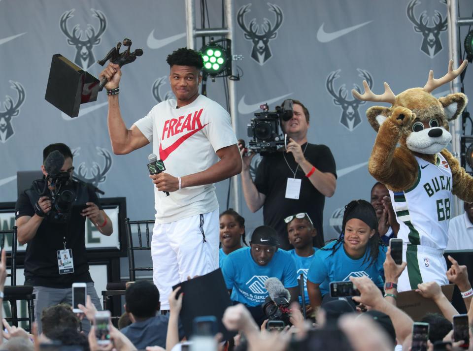 Giannis Antetokounmpo raises the first of his two NBA MVP trophies on the plaza at Fiserv Forum on July 14, 2019, during a celebration.