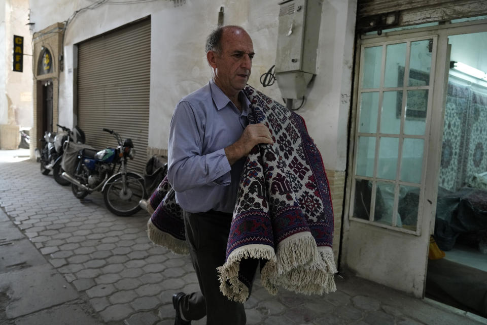 An Iranian man carries a carpet at the traditional bazaar of the city of Kashan, about 152 miles (245 km) south of the capital Tehran, Iran, Tuesday, April 30, 2024. (AP Photo/Vahid Salemi)