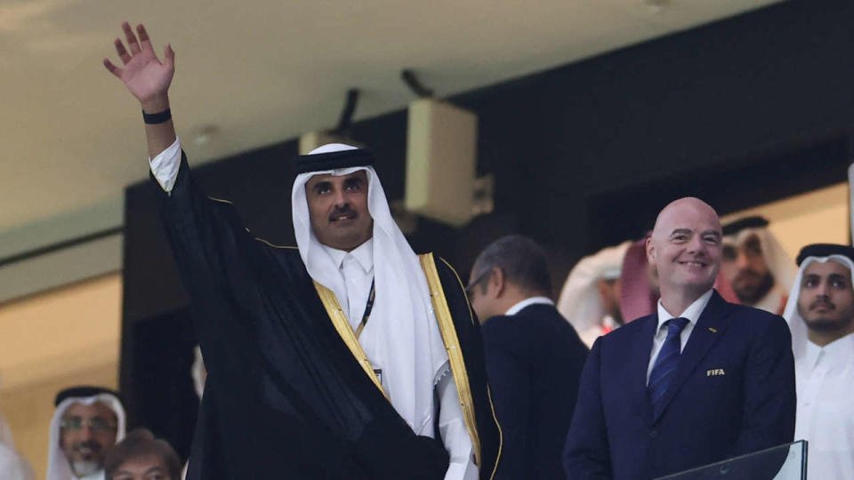 L’émir du Qatar, Sheikh Tamim bin Hamad al-Thani, salue la foule alors qu’il arrive avec le président de la FIFA, Gianni Infantino, pour le match de football du groupe A de la Coupe du monde 2022 entre le Qatar et l’Équateur au stade Al-Bayt à Al Khor, au nord de Doha, le 20 novembre 2022. (Photo par KARIM JAAFAR / AFP)