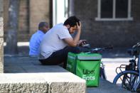 A bicycle courier from Uber Eats checks his phone in the shade during the heatwave in Utrecht