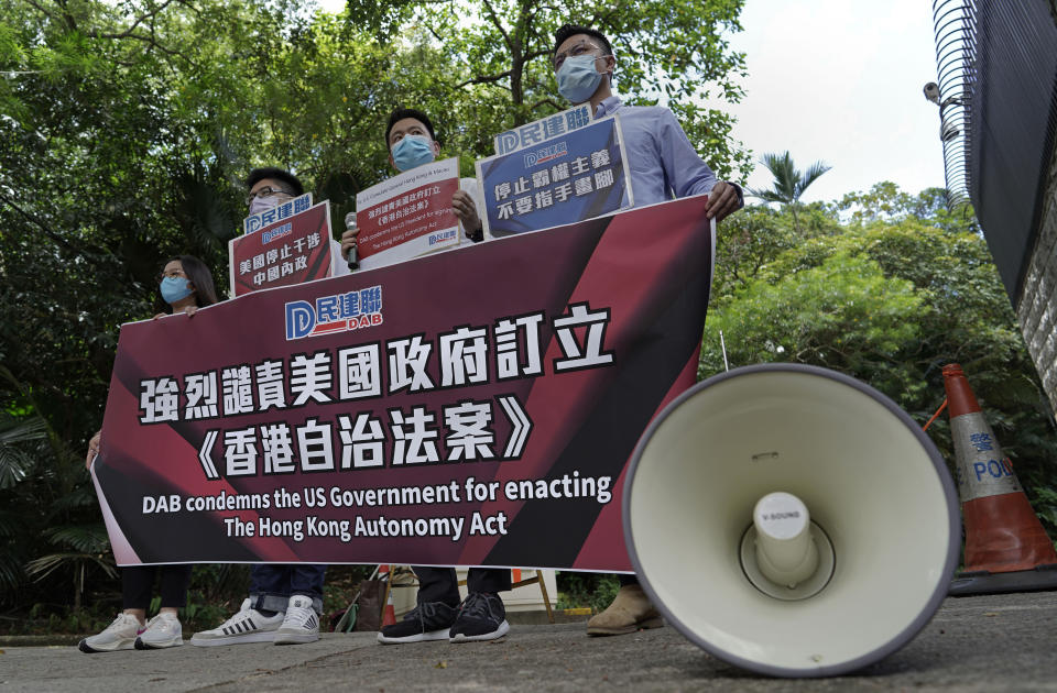 Beijing supporters carry a banner during a protest against the U.S. sanctions outside the U.S. Consulate in Hong Kong Thursday, July 16, 2020. China has accused the U.S. of seeking to obstruct its development with moves to sanction officials who undermine local autonomy in Hong Kong. (AP Photo/Vincent Yu)