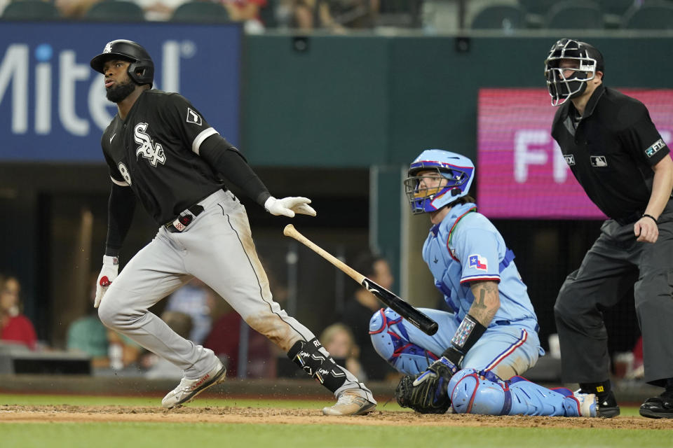 Chicago White Sox's Luis Robert, left, and Texas Rangers catcher Jonah Heim watch the ball Robert hit during the seventh inning of a baseball game in Arlington, Texas, Sunday, Aug. 7, 2022. Robert was safe at first base due to throwing error by Rangers third baseman Ezequiel Duran and White Sox's Leury Garcia scored on the play. (AP Photo/LM Otero)