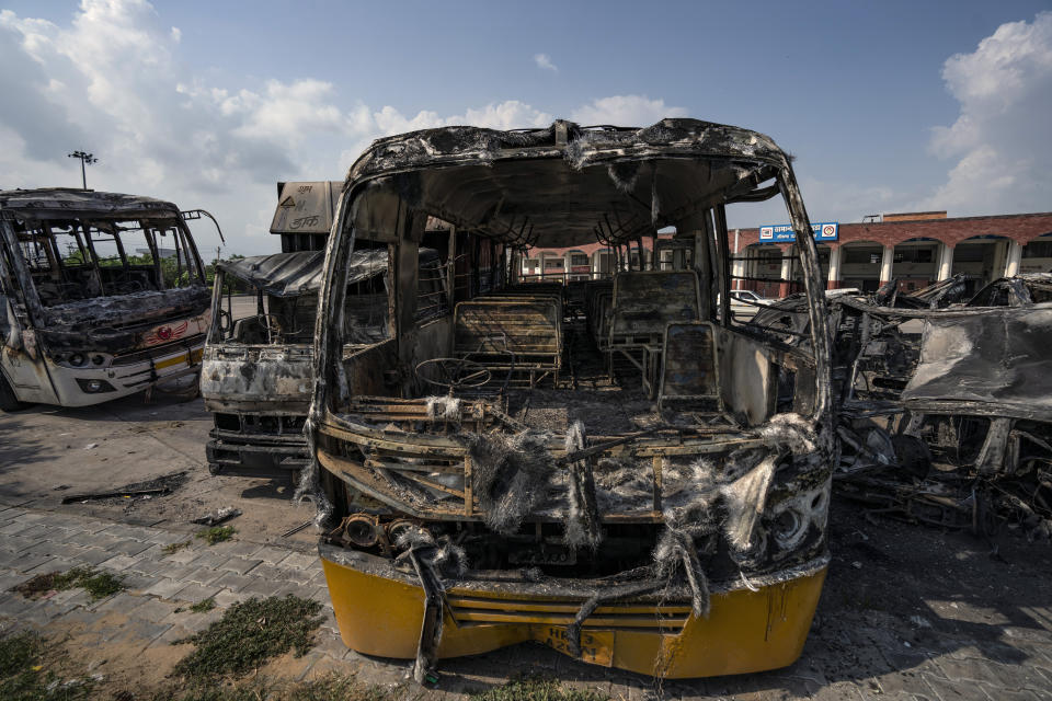 Burnt vehicles stand in a transport yard in Nuh in Haryana state, India, Tuesday, Aug., 1, 2023. Deadly clashes between Hindus and Muslims began in the area Monday afternoon during a religious procession by a Hindu nationalist group forcing Indian authorities to impose a curfew and suspend Internet services. (AP Photo/Altaf Qadri)