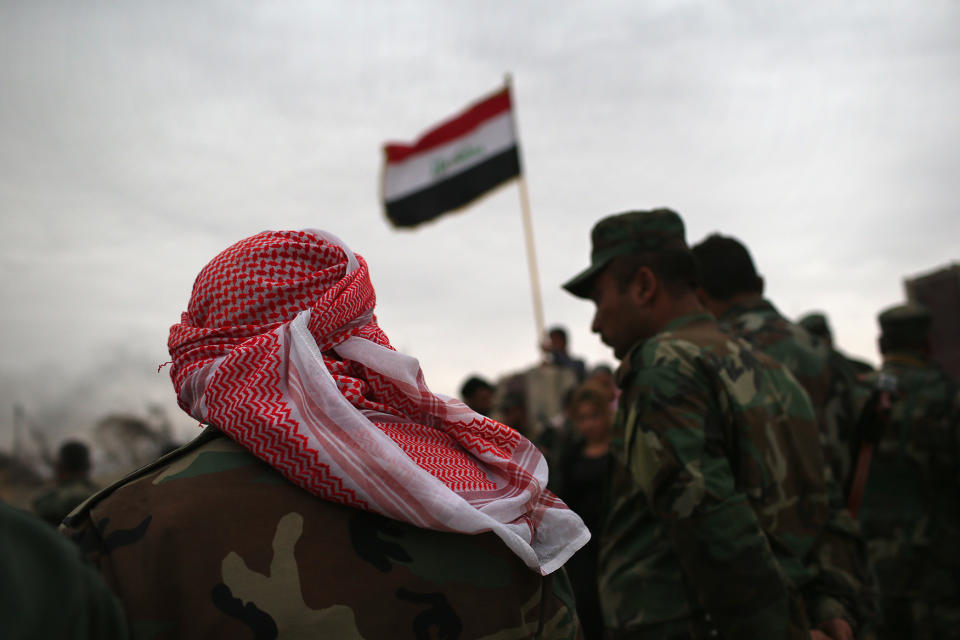 Iraqi Kurdish forces attend a flag-raising ceremony at a post office destroyed by an airstrike on Sinjar, Iraq. (John Moore/Getty Images)