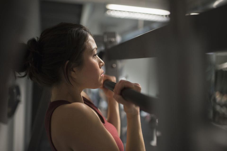 mixed race woman using exercise machine in gym