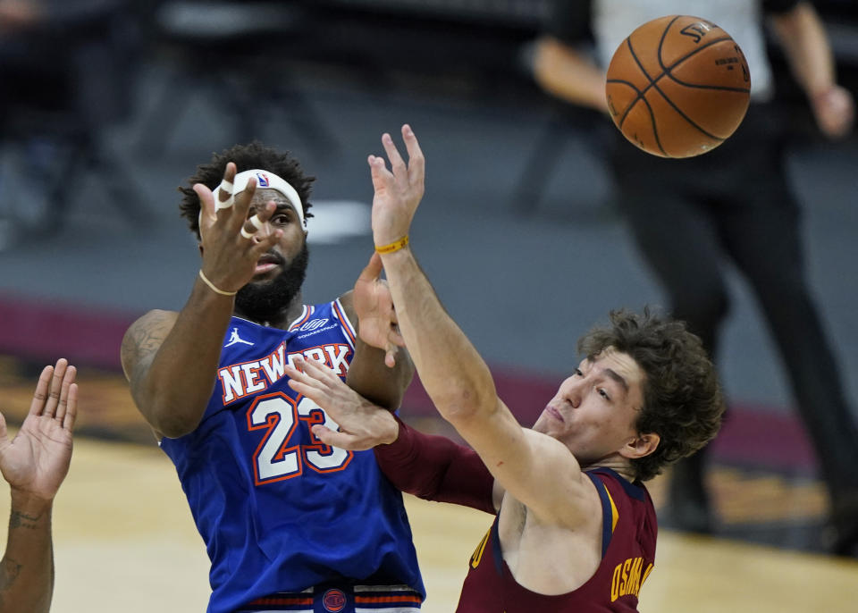 New York Knicks' Mitchell Robinson, left, loses control of the ball as he drives to the basket against Cleveland Cavaliers' Cedi Osman during the second half of an NBA basketball game Friday, Jan. 15, 2021, in Cleveland. Cleveland won 106-103. (AP Photo/Tony Dejak)