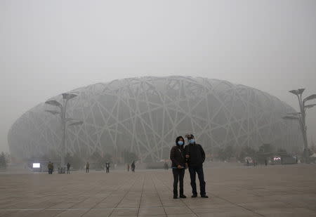 Visitors wearing protective masks take a selfie in front of the National Stadium, also known as the "Bird's Nest", on an extremely polluted day as hazardous, choking smog continues to blanket Beijing, China December 1, 2015. REUTERS/Kim Kyung-Hoon