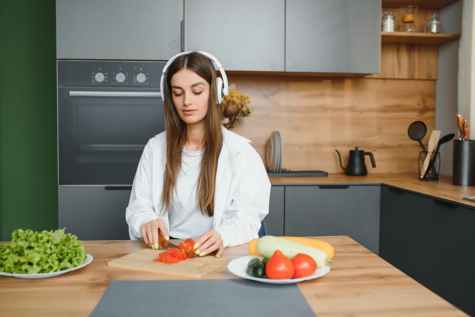 Una chica cocina mientras disfruta de un audiolibro - Getty