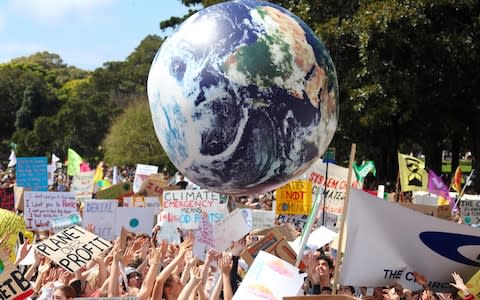 Protesters push an inflatable globe into the air while holding placards and banners during the Global Climate Strike demonstration at the Domain in Sydney - Credit: David Gray/Bloomberg