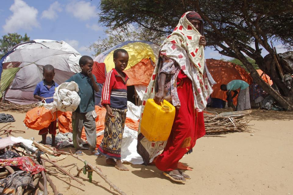 A woman walks with her children, who fled amid drought, to build a makeshift shelter at a camp for the displaced people on the outskirts of Mogadishu, Somalia on Tuesday, Sept. 26, 2023. (AP Photo/Farah Abdi Warsameh)
