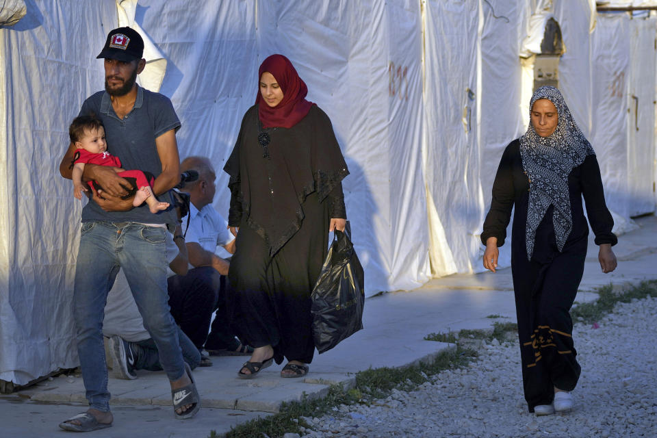 Syrian refugee families walk back into a refugee camp after running errands in the town of Bar Elias, in the Bekaa Valley, Lebanon, July 7, 2022. The Lebanese government’s plan to start deporting Syrian refugees has sent waves of fear through vulnerable refugee communities already struggling to survive in their host country. Many refugees say being forced to return to the war shattered country would be a death sentence. (AP Photo/Bilal Hussein)