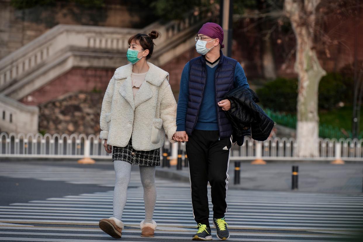 This photo taken on March 12, 2020 shows residents wearing face masks as a preventive measure against the COVID-19 coronavirus walking along a street in Wuhan in China's central Hubei province. - China reported just eight cases of the covid-19 coronavirus outbreak on March 13, with no new domestic infections outside the epicentre of Hubei province. (Photo by STR / AFP) / China OUT (Photo by STR/AFP via Getty Images)