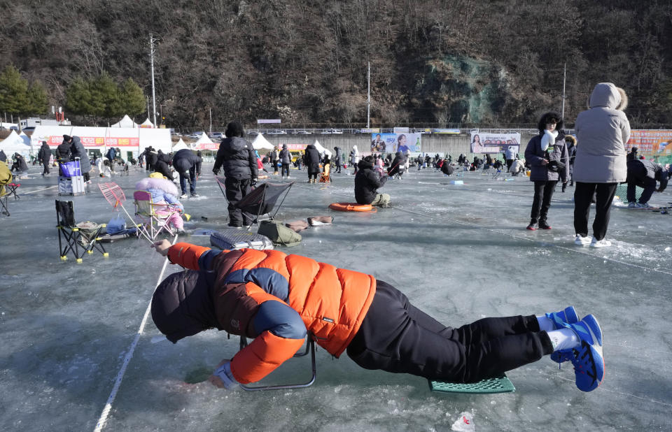 A man casts a line through a hole drilled in the surface of a frozen river during a trout catching contest in Hwacheon, South Korea, Saturday, Jan. 6, 2024. The contest is part of an annual ice festival which draws over one million visitors every year. (AP Photo/Ahn Young-joon)
