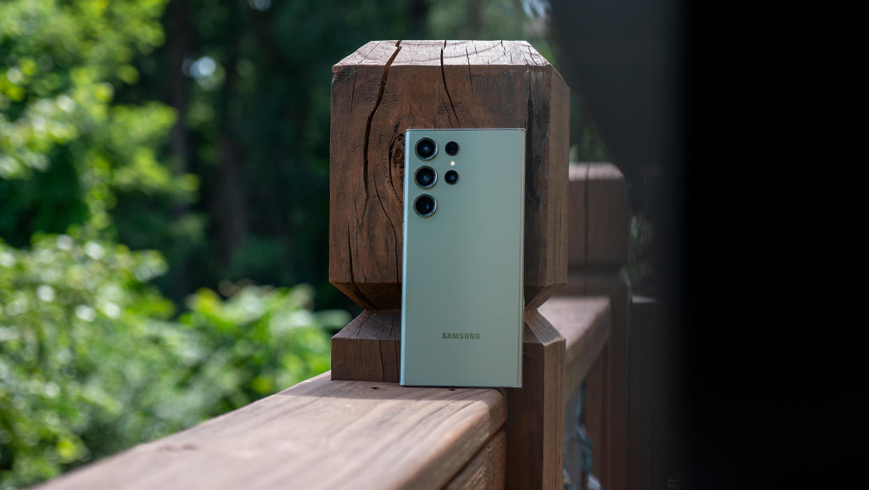  The green Samsung Galaxy S23 Ultra leaning against a wooden deck railing. 