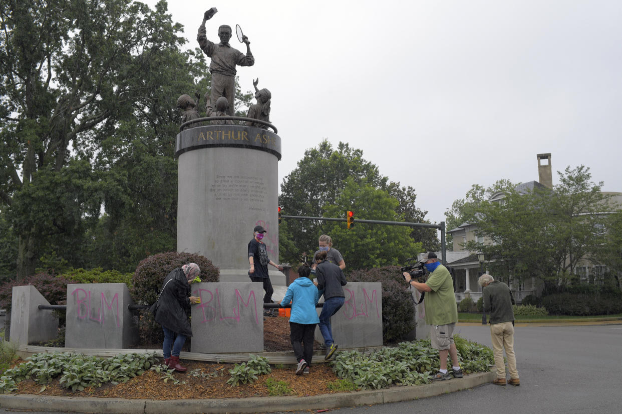  Volunteers use cleaning agents to clean off spray-painted graffiti off of the Arthur Ashe memorial in Richmond, Virginia, on June 17.