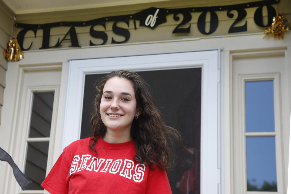 In this June 1, 2020 photo, high school graduate Lizzie Quinlivan poses at her home in Hingham, Mass. Quinlivan has opted to attend closer-to-home Georgetown instead of colleges on the west coast which were on her original wish-list. As students make college plans for this fall, some U.S. universities are seeing surging interest from in-state students looking to stay closer to home amid the coronavirus pandemic.(AP Photo/Elise Amendola)