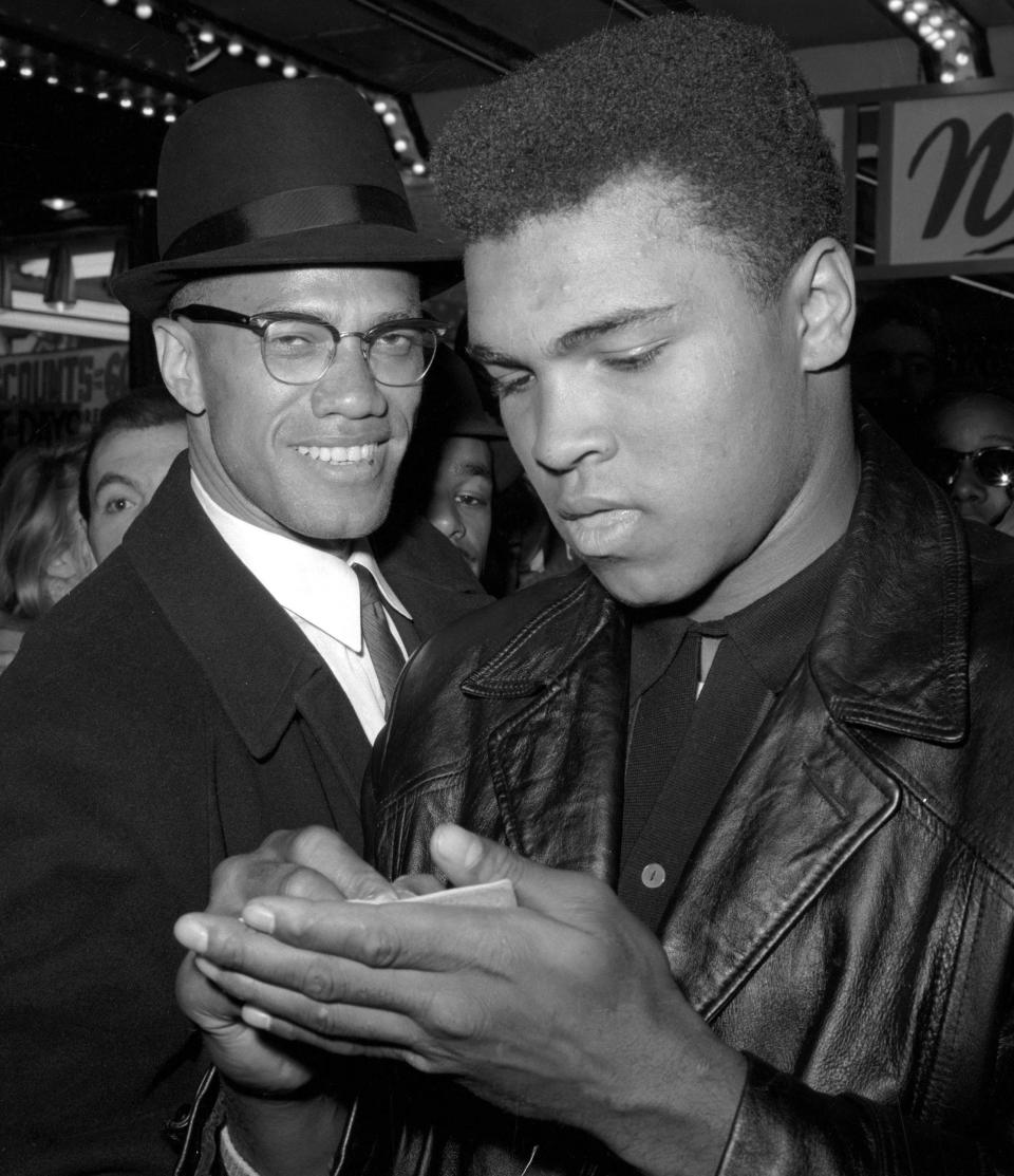 In this March 1, 1964, photo, heavyweight boxing champion Muhammad Ali, right, is shown with black muslim leader Malcolm X outside the Trans-Lux Newsreel Theater in New York, after viewing the screening of a film about Ali's title fight with Sonny Liston. (AP Photo/File)