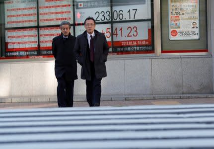 Pedestrians walk past an electronic board displaying the Nikkei average outside a brokerage in Tokyo, Japan January 4, 2018. REUTERS/Kim Kyung-Hoon