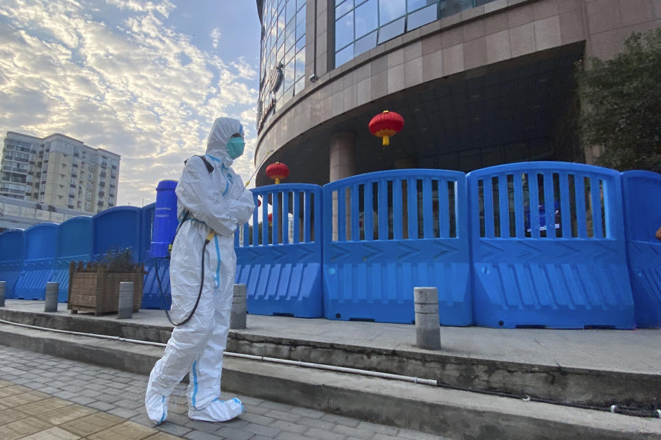 A worker in protectively overalls and disinfecting equipment walks outside the Wuhan Central Hospital where Li Wenliang, the whistleblower doctor who sounded the alarm and was reprimanded by local police for it in the early days of Wuhan's pandemic, worked in Wuhan in central China's Hubei province on Saturday, Feb. 6, 2021. Dr. Li Wenliang died in the early hours of Feb. 7 from the virus first detected in this Chinese city. A small stream of people marked the anniversary at the hospital. The 34-year-old became a beloved figure and a potent symbol in China after it was revealed that he was one the whistleblowers who authorities had punished early for “spreading rumors” about a SARS-like virus. (AP Photo/Ng Han Guan)