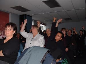 Many people raising their hands at a conference
