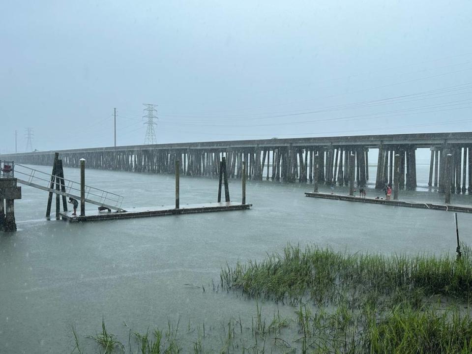 A family and a sole angler fishing in the rain at the C. C. Haigh, Jr. boat landing dock beside the Hilton Head Island bridge.