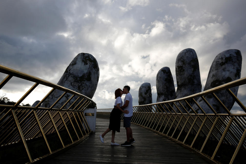 A young couple kisses near the giant hands.