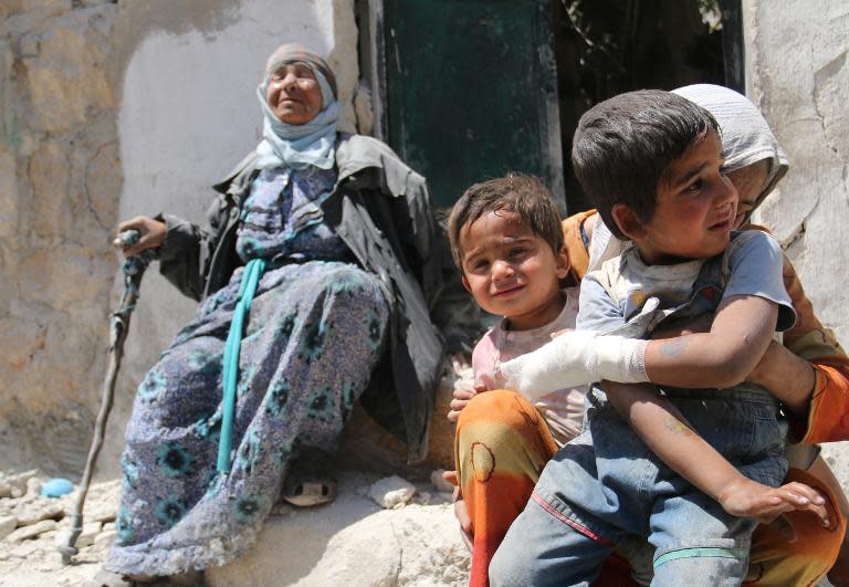 A Syrian woman comforts her children after their house in the Sahour neighbourhood of the northern Syrian city of Aleppo was bombed on May 14, 2014