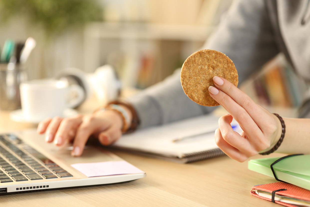 Woman pictured consuming snacks while working from home. (Getty Images)