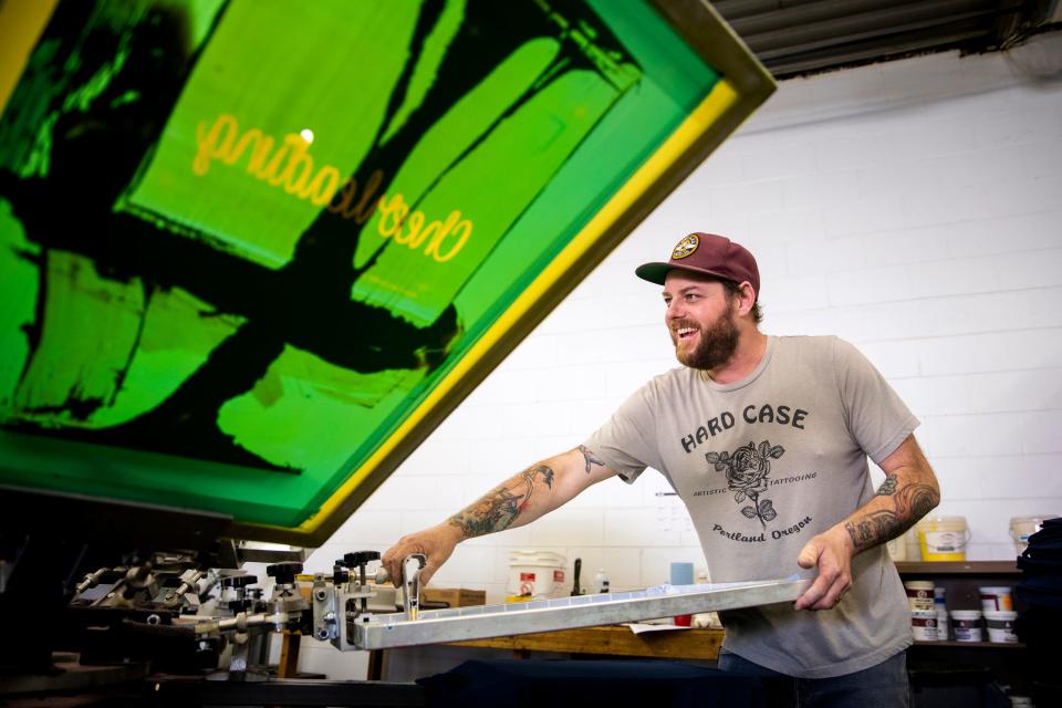 Brandon Swinehart of Cincinnati screen presses T-shirts at SRO Prints, the company he co-founded with his wife. Swinehart, who struggled with addiction, has been clean for 18 years and, in hiring for the business, gives people in recovery second chances.