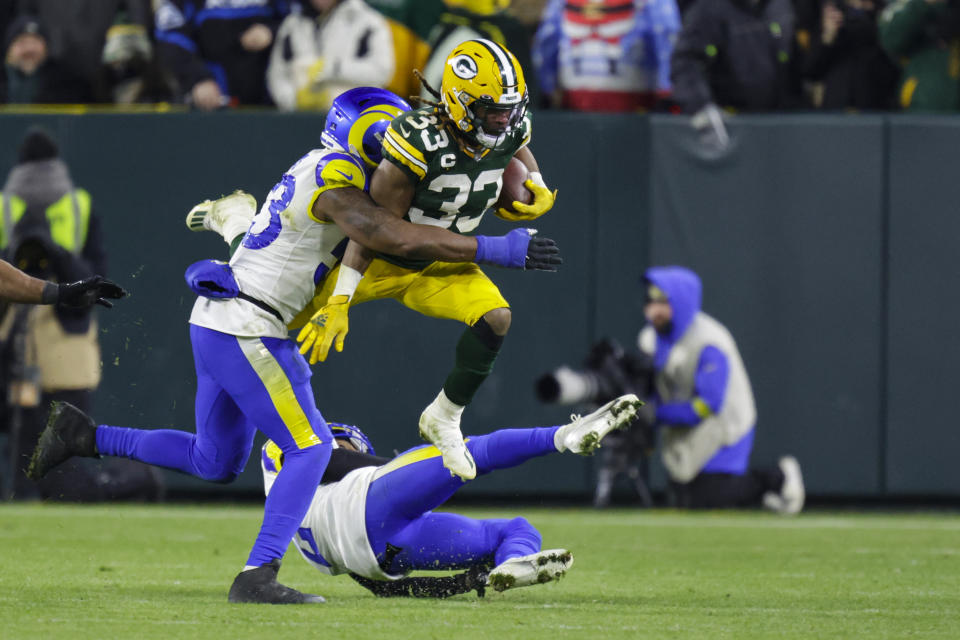 Green Bay Packers running back Aaron Jones (33) leaps over Los Angeles Rams cornerback Troy Hill (2) as he's hit by linebacker Ernest Jones (53) in the second half of an NFL football game in Green Bay, Wis. Monday, Dec. 19, 2022. (AP Photo/Matt Ludtke)