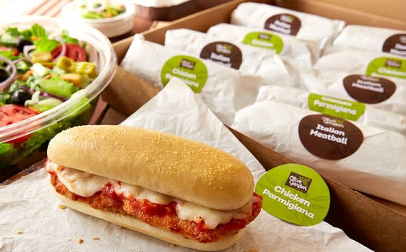 A spread of Olive Garden catered sandwiches and a salad.