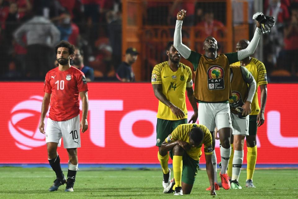 Egypt's forward Mohamed Salah (L) reacts as South Africa's players celebrate during the 2019 Africa Cup of Nations (CAN) Round of 16 football match between Egypt and South Africa at the Cairo International Stadium in the Egyptian Capital on July 6, 2019. (Photo by OZAN KOSE / AFP)        (Photo credit should read OZAN KOSE/AFP/Getty Images)