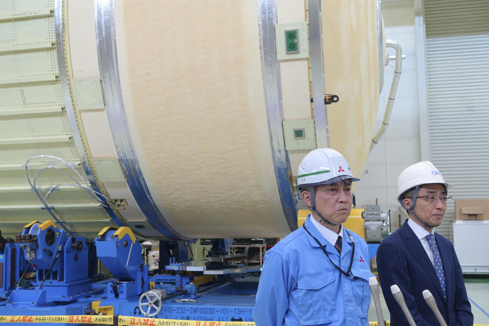 FILE - JAXA H3 rocket project managers Masashi Okada, right, and Mayuki Niitsu brief journalists in front of the second stage of a H3 rocket, set for a full-fledged launch later this year after two test flights, inside the Mitsubishi Heavy Industries' Nagoya Aerospace Systems Works Tobishima Plant in Tobishima, Aichi prefecture Thursday, March 21, 2024. Japan’s space agency announced Friday, April 26, that it will launch its new flagship rocket H3 on June 30 carrying an observation satellite for disaster response and security purposes, a key mission that it had failed in its debut flight last year. (AP Photo/Mari Yamaguchi, File)