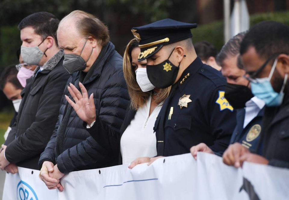 Fresno Unified board member Keshia Thomas, center, raises her hand during prayer as she joins other dignitaries before the start of the annual MLK march Monday morning, Jan. 17, 2022 in downtown Fresno.