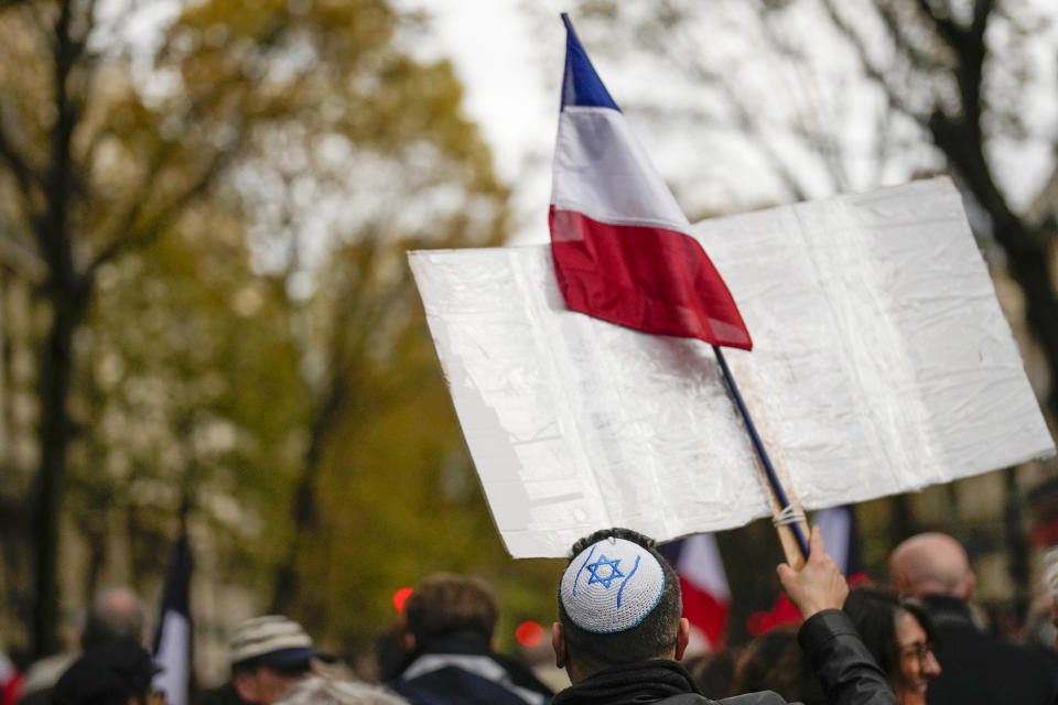 A demonstrator wearing a kippa and holding a French flag joins thousands who gathered for a march against antisemitism in Paris, France, Sunday, Nov. 12, 2023. French authorities have registered more than 1,000 acts against Jews around the country in a month since the conflict in the Middle East began. (AP Photo/Christophe Ena)