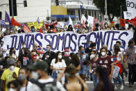 People march holding a banner with a message that reads in Portuguese; "Together, we are giants" during a demonstration against Brazilian President Jair Bolsonaro's handling of the coronavirus pandemic and economic policies protesters say harm the interests of the poor and working class, in Rio de Janeiro, Brazil, Saturday, June 19, 2021. Brazil is approaching an official COVID-19 death toll of 500,000 — second-highest in the world. (AP Photo/Bruna Prado)