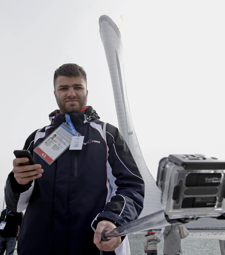 Alexey Khavkin takes a selfie in front of the Olympic Cauldron at the 2014 Winter Olympics, Sunday, Feb. 9, 2014, in Sochi, Russia. (AP Photo/Morry Gash)