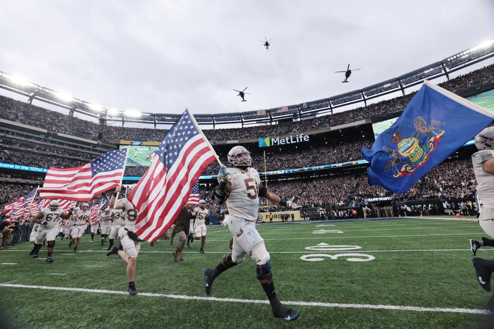 Army offensive lineman Kamaron Holloway (51) runs on the field with teammates as the 160th Special Operations Aviation Regiment flies over before the game against the Navy Midshipmen at MetLife Stadium.