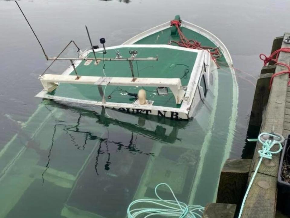 The Canadian Coast Guard says it will remove this fishing boat from the Tickle Wharf in Canso and recover the cost later. RCMP say it is too soon to determine if the sinking was accidental or deliberate.  (Facebook/Kyle Horne - image credit)