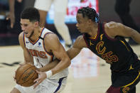 Phoenix Suns' Devin Booker, left, drives past Cleveland Cavaliers' Isaac Okoro in the first half of an NBA basketball game, Tuesday, May 4, 2021, in Cleveland. (AP Photo/Tony Dejak)