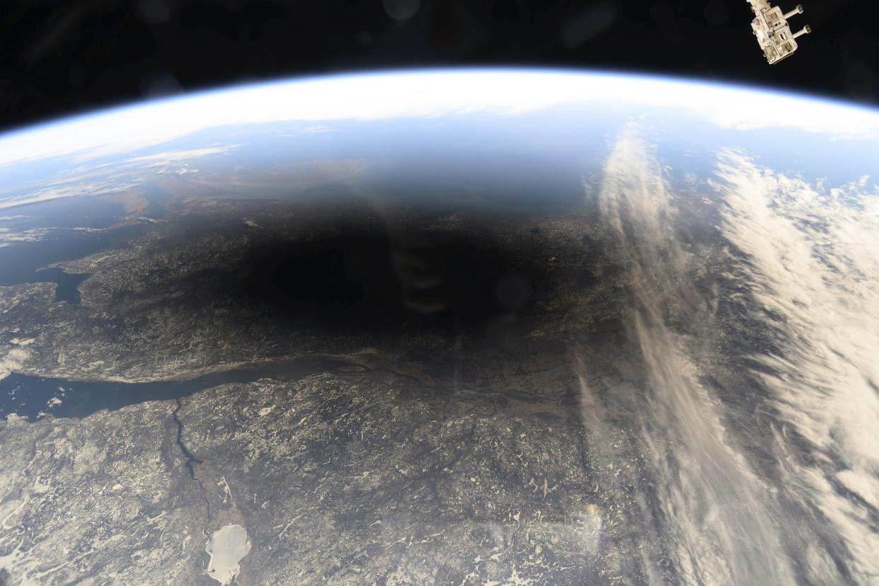 Image from space showing round black shadow on the face of the Earth.