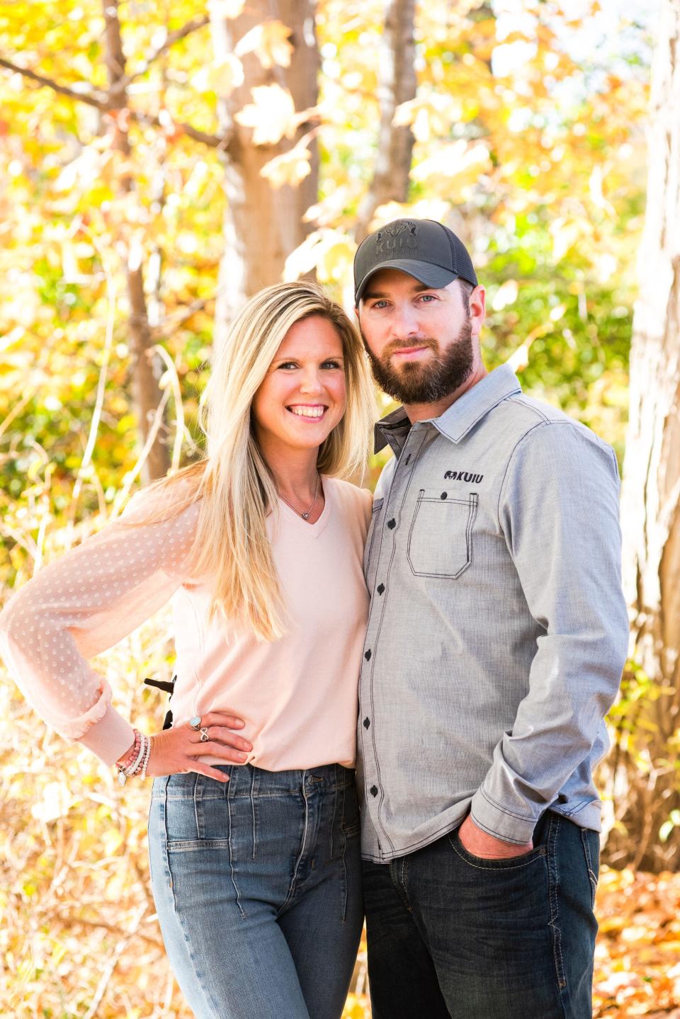 Meghan Thomas poses against a backdrop of trees with her husband, Ian.