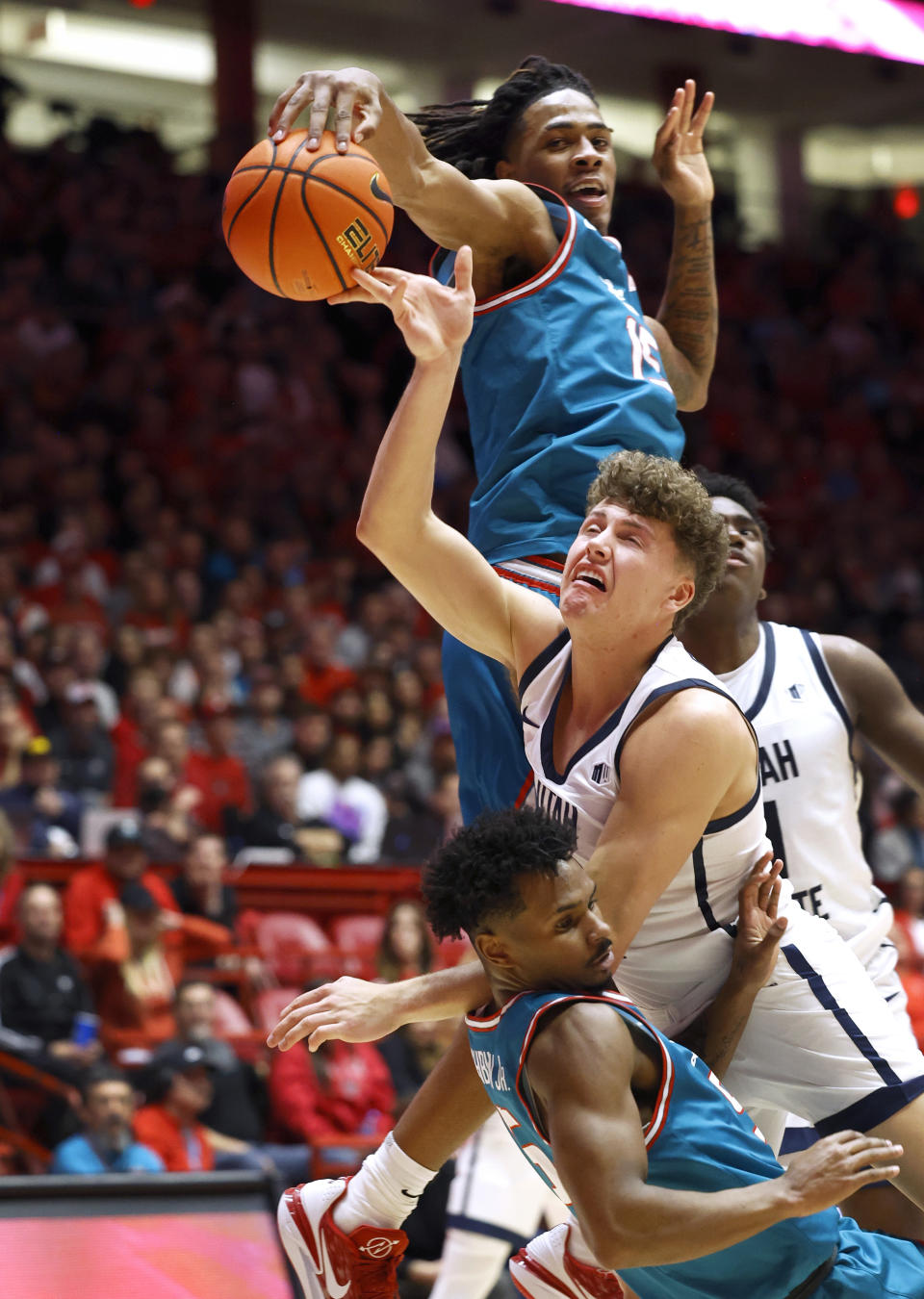 Utah State guard Mason Falslev attempts a layup as New Mexico forward JT Toppin blocks it and New Mexico guard Jamal Mashburn Jr. defends during the first half of an NCAA college basketball game Tuesday, Jan. 16, 2024, in Albuquerque, N.M. (AP Photo/Eric Draper)