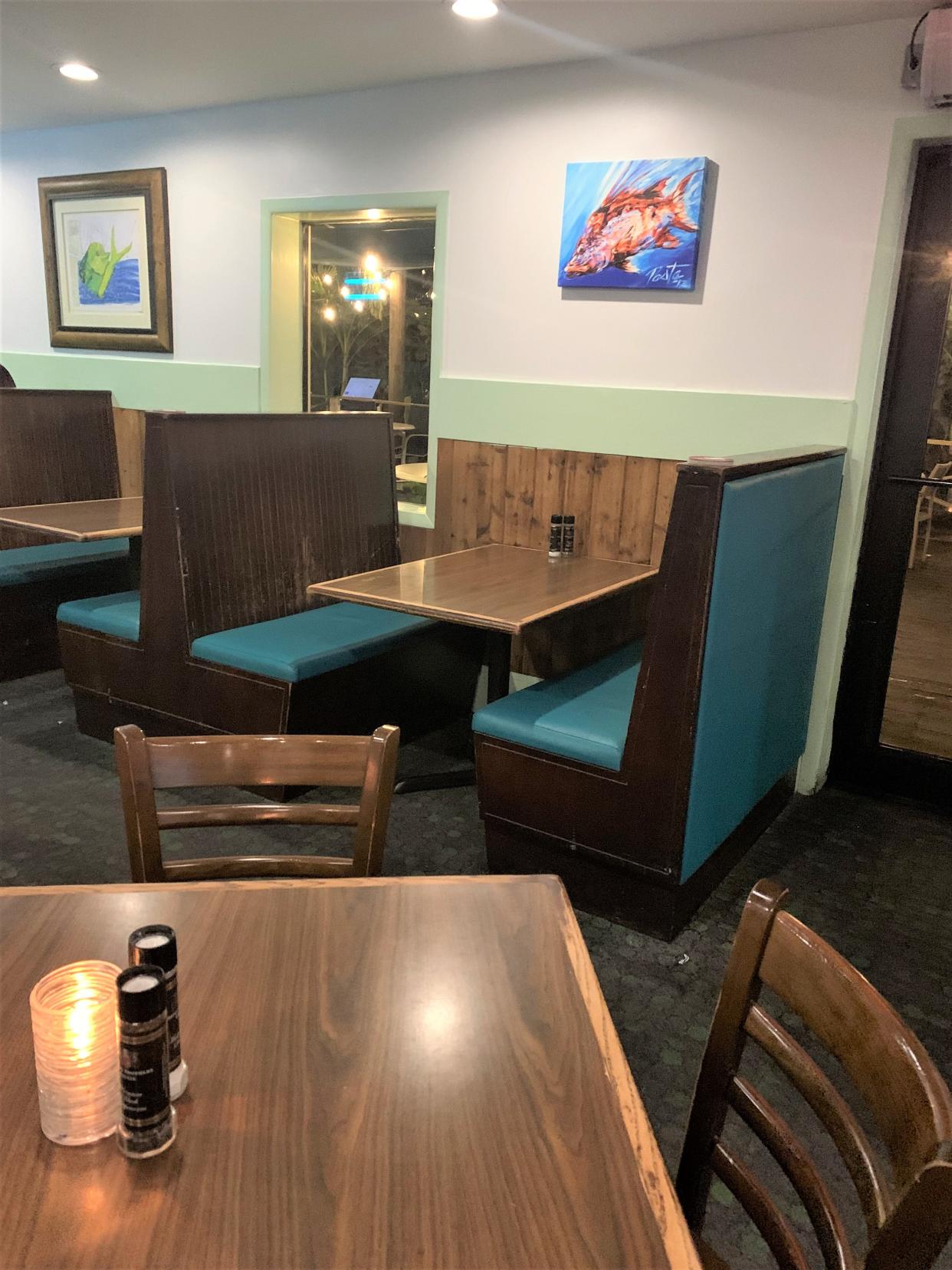 The main dining area at 12A Buoy features teal leather and wood booths or wooden tables and chairs.