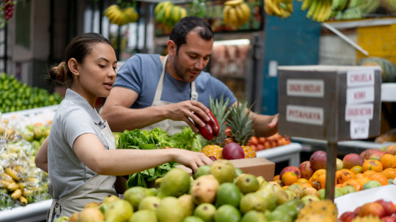 man and woman stocking fruits 