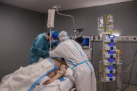 A medical team of the new Nurse Isabel Zendal Hospital check a patient inside a COVID-19 ICU in Madrid, Spain, Monday, Jan. 18, 2021. As the coronavirus curve of contagion turned increasingly vertical after Christmas and New Year's, the Zendal has been busy. On Monday, 392 virus patients were being treated, more than in any other hospital in the Madrid region. (AP Photo/Bernat Armangue)