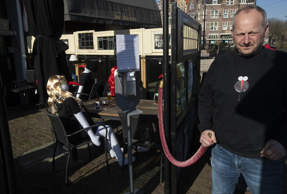 Owner Peter Bender of cafe De Ooievaar closes his terrace filled with inflatable dolls in Delfshaven, Rotterdam, Netherlands, Tuesday, March 2, 2021. Stores in one village opened briefly, cafe owners across the Netherlands were putting tables and chairs on their outdoor terraces and sex workers were planning a demonstration outside parliament in protests against the government's tough coronavirus lockdown. (AP Photo/Peter Dejong)