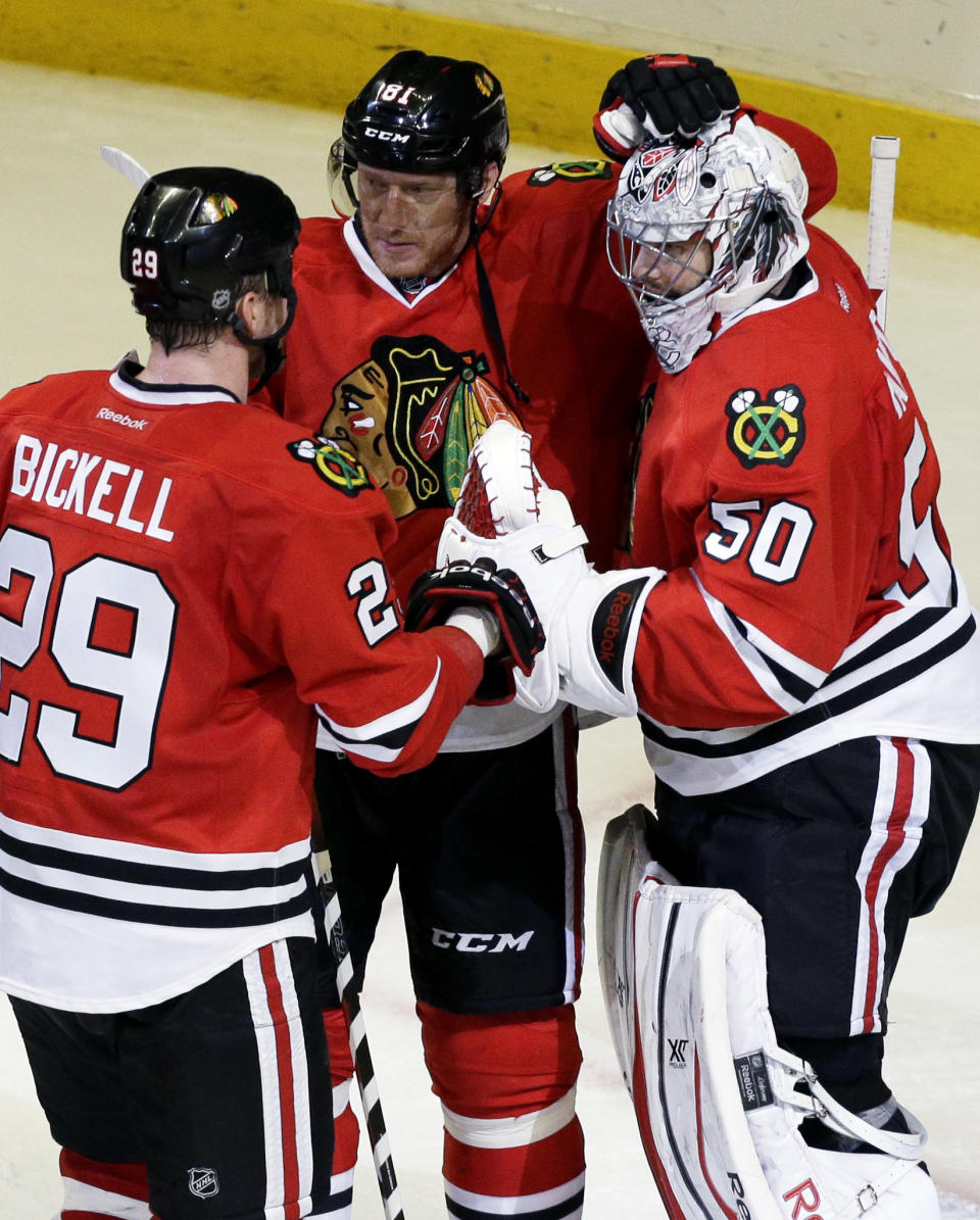 Chicago Blackhawks goalie Corey Crawford (50) celebrates with teammates Marian Hossa (81) and Bryan Bickell (29) after they defeated the St. Louis Blues 5-1 in Game 6 of a first-round NHL hockey playoff series in Chicago, Sunday, April 27, 2014. (AP Photo/Nam Y. Huh)