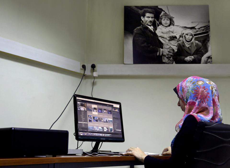 In this Monday, May 12, 2014 photo, Alla Al Agha, an employee in the photo archive of the United Nations Relief and Works Agency (UNRWA), edits photos at the UNRWA archive library in Gaza City, in the northern Gaza Strip. Last year, a $1 million digitization project began with funding from Denmark, France and the Palestinian private sector. An online database already has close to 2,000 images preserving a record of one of the world's most entrenched refugee problems, created in what the Palestinians call the "Nakba," or “catastrophe” -- their uprooting in the war over Israel's 1948 creation. (AP Photo/Adel Hana)