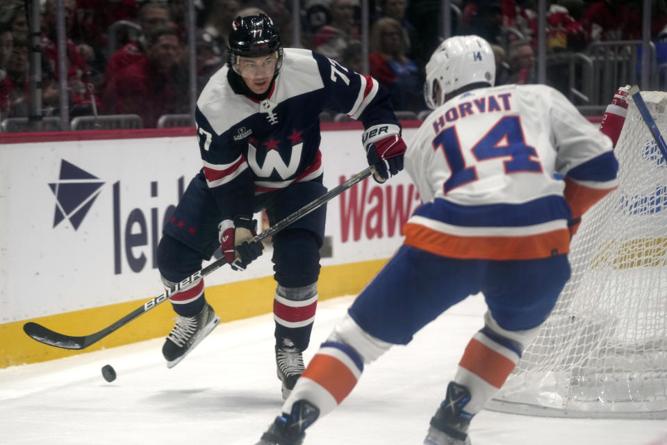 Washington Capitals right wing T.J. Oshie, left, looks to pass the puck around New York Islanders center Bo Horvat (14) in the first period of an NHL hockey game, Thursday, Nov. 2, 2023, in Washington. (AP Photo/Mark Schiefelbein)